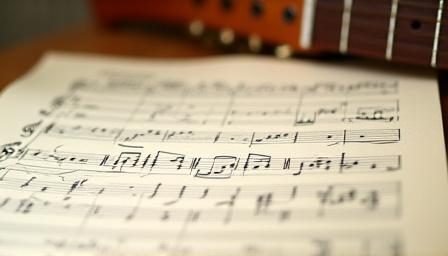 Student studying music theory sheet and guitar together